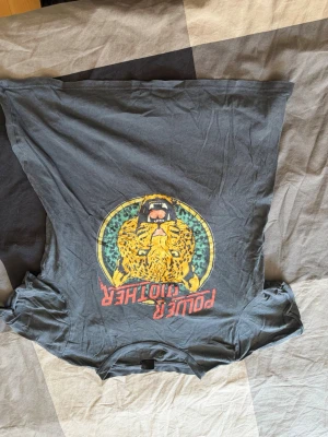 Grå t-shirt med leopardtryck - Cool grå t-shirt med färgglatt leopardtryck och texten 'POWER CLOT HER' på framsidan. T-shirten har rund hals och korta ärmar, perfekt för en avslappnad streetstyle-look.