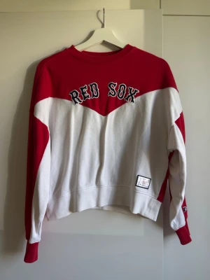 sweatshirt från Champion - Snygg röd och vit sweatshirt från Champion med Red Sox-tryck på bröstet. Tröjan har rund halsringning, långa ärmar och en patch nertill. 