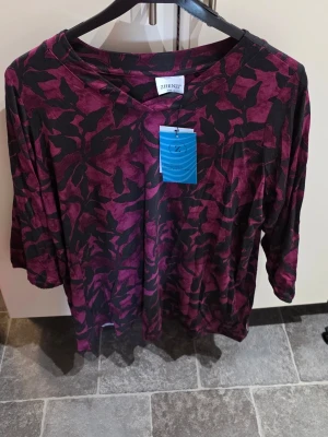 Mönstrad topp från Zhenzi - Cool topp från Zhenzi i mörklila och svart med abstrakt mönster. Toppen har trekvartsärm och en avslappnad passform, perfekt för dig som gillar att sticka ut lite extra. Tillverkad i mjukt material som känns skönt mot huden.