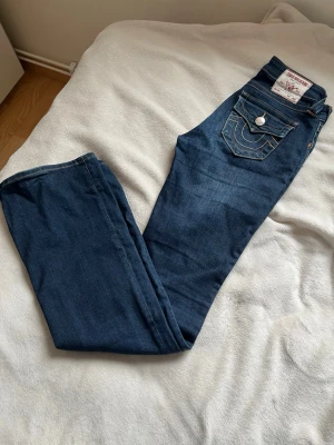 Mörkblå True Religion jeans - Säljer ett par mörkblå jeans från True Religion i strl 25. Dom är lowwaist och passar för  någon som är 165+ skulle jag säga om man inte vill sy upp dom . Jag är 173 och dom sitter bra i längden och dom sitter lowwaist på mig. Pris kan diskuteras! Dom är i jätte bra skick. Hör av er om ni har några frågor💕
