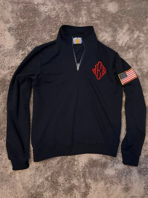 Epstein quarter zip - Mörkblå långärmad Epstein tröja med halv dragkedja. Amerika flaggan på sidan och JEE på bröstet. Den är helt ny och är i perfect skick.