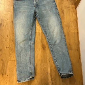 Nudie jeans herr ljusblå  - Säljer ett par ljusblå jeans med rak passform och klassisk framficksdesign från nudie. Jeansen har slitningar och tvättade detaljer för en avslappnad look. Perfekta till sneakers eller boots och passar dig som gillar en enkel men snygg stil. det är storlek 32-30 men passar mig som e 185 