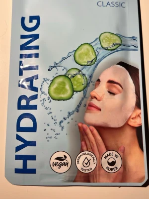 Hydrating sheet mask med gurka - Återfuktande sheet mask med gurka, perfekt för att ge huden extra fukt. Masken är vegansk, dermatologiskt testad och tillverkad i Korea. Förpackningen har blå och vita färger med gurkdesign.