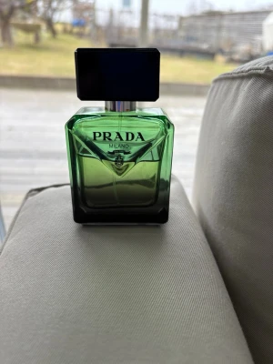 Prada parfymflaska mörkgrön - Snygg parfym från Prada i en stilren, mörkgrön glasflaska med svart fyrkantigt lock. Flaskan har en modern och lyxig design som sticker ut i badrumshyllan. Perfekt för dig som gillar exklusiva dofter och vill ha något från ett välkänt märke.