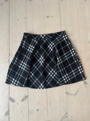 Svartvit rutig kortkjol - Kortkjol i svart och vitt med rutigt mönster. Kjolen har en lätt utställd form och är tillverkad i ett mjukt material som ger en skön känsla. Perfekt att matcha med en enkel topp eller stickad tröja.