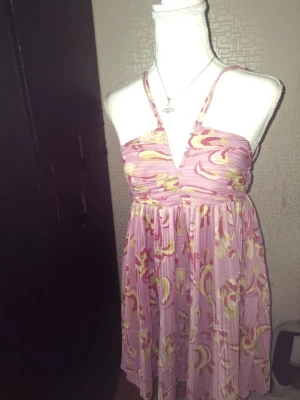 Rosa Zara blommig kortklänning - Söt rosa kortklänning med blommigt mönster och smala axelband. Klänningen har omlott över bysten och ett fallande, luftigt tyg som ger en avslappnad känsla. Perfekt för varma dagar och sommarens alla tillfällen.