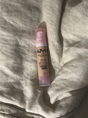 NYX Bare With Me Concealer Serum - NYX Bare With Me Concealer Serum i en ljus beige nyans med färgen vanilla Kommer i en smidig plasttub med pump och rosa detaljer. Perfekt för att täcka mörka ringar och ojämnheter. Lätt formula som smälter in i huden och ger ett naturligt resultat. Den är helt ny aldrig använd men såg redan på förpackningen att de va fel färg köpt på nätet så där av inte lämnat tillbaka den.