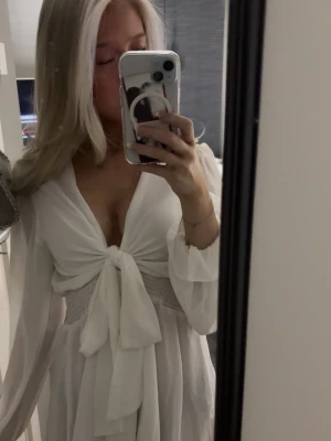 Vit omlottklänning med knyt - Supersöt vit kortklänning med omlott och knyt framtill. Köpe den till nians avslutning men har aldrig använt den pga att den är för stor i bysten.