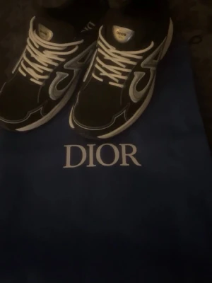 Dio svartvita sneakers - Snygga svartvita sneakers från Dio med vita detaljer och logotyp på sidan. Skorna har vita snören och en tjock vit sula som ger en modern look. Materialet är en mix av textil och läder, perfekt för dig som vill sticka ut med exklusiva sneakers.