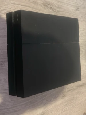 PlayStation 4 svart spelkonsol - Säljer en svart PlayStation 4 från Sony. Konsolen har en stilren, rektangulär design med matta och blanka ytor. Perfekt för gaming och streaming. Tillverkad i plast och passar till alla PS4-spel.
