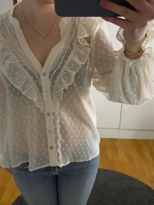 Vit blus med volanger från Zara -  vit blus från Zara med prickigt mönster. Blusen har volanger och v-ringning storlek. xs men passar S 