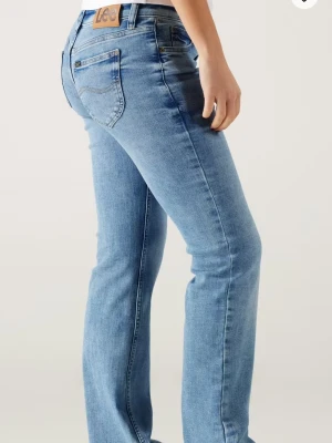 Ljusblå low waist bootcut jeans från Lee - Säljer ett par ljusblå bootcut jeans från Lee med klassisk femficksdesign och läderpatch bak i midjan. Jeansen är low waisted och i bra skick utöver det lilla slitna på bild 5! Nypris: 1099kr. Säljer då dem blivit för små för mig❣️❣️