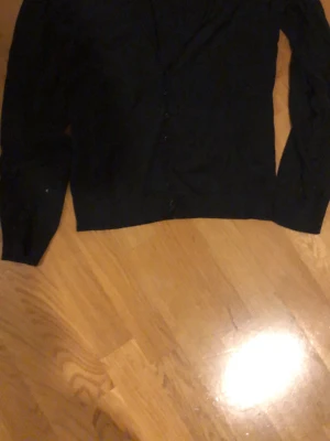 Svart kofta från Esprit - Klassisk svart kofta från Esprit med knäppning framtill. Enkel och stilren design med långa ärmar och rund halsringning. Perfekt att slänga över en t-shirt eller linne för en clean look.