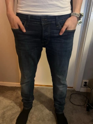 Mörkblå slim fit jeans ifrån jack and jones - Schyssta mörkblåa jeans ifrån jack and jones. Slimfit glenn i strlk 33/34. Köpta för 900kr. Gott skick. Pris går att diskutera.