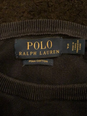 Marin blå tröja från Polo Ralph Lauren - Klassisk marinblå tröja från Polo Ralph Lauren i mjuk pima cotton. Tröjan har rund halsringning, långa ärmar och den ikoniska broderade loggan på bröstet. Perfekt för en stilren och enkel look.