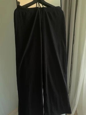 Svarta ribbade linnebyxor från 157 - Svarta ribbade linnebyxor från 157 i storlek M. De har en elastisk midja med dragsko och är tillverkade i ett mjukt, stretchigt material. Trodde de var högmidjade när jag köpte dom men de visade sig vara lågmidjade. Helt nya och oanvända. (Förra årets design)