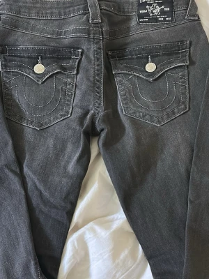 Gråa True Religion jeans Joey - Snygga gråa jeans från True Religion, modell Joey med låg midja och bootcut. Jeansen är nya. Köparen står för priset + frakten. 
