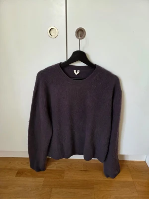 Mörkgrå stickad tröja - Mysig mörkgrå stickad tröja med rund halsringning och lång ärm. Tröjan har en fluffig yta och avslappnad passform, perfekt för lager-på-lager. Passar dig som gillar enkel och stilren design.