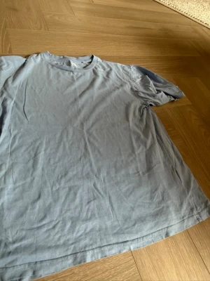 Blå basic t-shirt i bomull - Enkel blå t-shirt i mjuk bomull med rund hals och korta ärmar. Perfekt till jeans eller shorts för en avslappnad look. Klassisk passform och utan tryck eller mönster.