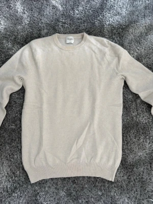 Beige cashmeretröja från John Henric - Mjuk och lyxig beige stickad tröja från John Henric i 100% cashmere. Passar bra till alla årstider dock har den ett litet hål i armhålan vilket går att sy om man nu har bra kunskap inom det därav priset 550kr