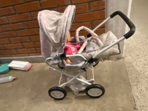 Ljusrosa prickig väst till docka - Söt ljusrosa vagn till docka med små vita prickar och hjärtmotiv. Vagn har en enkel design och är perfekt för att klä upp dockan. Passar bra till lek och pyssel med dockvagn.
