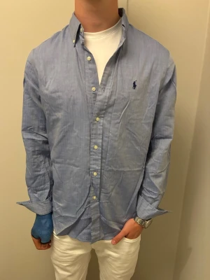 Ralph Lauren skjorta - Tja, säljer nu denna feta Ralph Lauren skjortan i mycket fina skick. Skjortan är i storlek ”M” och vid frågor eller funderingar är det bara att höra av sig! (Skjortan kan se lite sne ut pga mitt gips, även lite fläckig med det är den INTE, ursäktar för detta) 