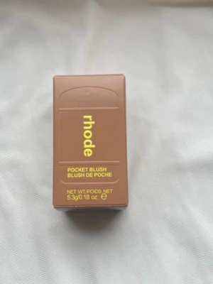 Rhode Pocket Blush Tan Line - Rhode Pocket Blush i nyansen Tan Line är ett kompakt rouge i en varm, brunrosa ton. Förpackningen är stilren och brun med gul text, och innehåller 5,3 g produkt. Perfekt att ha med i väskan för snabba touch-ups. Ger en naturlig, solkysst look.