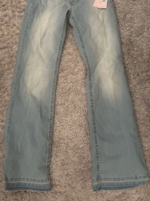 Ljusblå bootcut jeans från Nelly - Snygga ljusblå bootcut jeans från Nelly med klassisk femficksdesign och slitna detaljer framtill. Jeansen har normal midja och är tillverkade i denim med lätt stretch för skön passform. Perfekta för en avslappnad och trendig look.