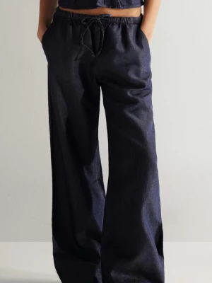 Mörkblå wide leg jeans med dragsko - Säljer ett par mörkblå denim byxor med breda ben och avslappnad passform. Jeansen har resår och dragsko i midjan för extra komfort. Tillverkade i denim och perfekta för en chill och trendig look.
