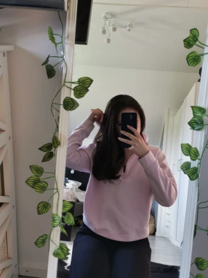 Ljusrosa hoodie med dragkedja - Säljer en ljusrosa hoodie med halv dragkedja framtill och huva. Hoodien har en avslappnad passform och är tillverkad i ett mjukt material som känns skönt mot huden. Perfekt för en chill och stilren look.