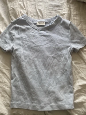 Tshirt - Ljusblå t-shirt från gina tricot. En liten fläck som knappt syns (se sista bilden). Färgen motsvarar sin rintiga mest på bild nmr 2