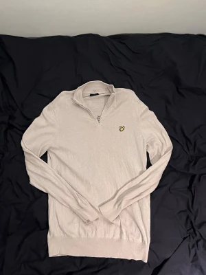 Beige tunn stickad tröja - En stilren och tunnstickad beige tröja med rund hals och långa ärmar. Perfekt för lager-på-lager och enkel att matcha med olika outfits. Tröjan har ribbade muddar vid ärmslut och nederkant för en snygg passform.