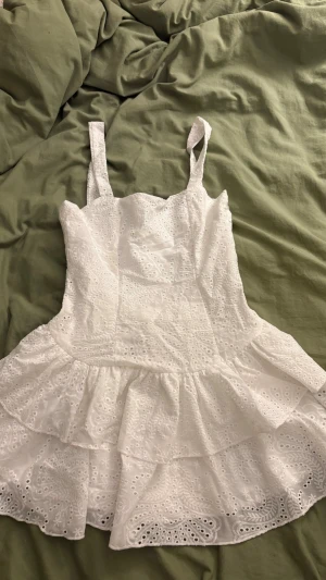 Vit  kort klänning med volang - Superfin vit klänning med broderade detaljer och volanger. Helt oanvänd då den är för liten, super bra skick!! Perfekt för sommaren. XS/XXS
