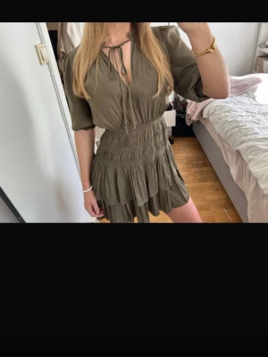 Maje klänning - Jätte fin grön volang klänning från Maje. Klänningen är kort och i siden/satin material. Den faller jätte fint och formar kroppen. Det finns knyten vid halsen. Klänningen sitter som en storlek xs/S men den är också i ett ganska stretchigt material så passar även S/M. Inga defekter. Hör gärna av er vid frågor 🥰