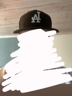 Svart LA-keps med rak skärm - Snygg svart keps från New Era med LA-logga i vitt framtill. Klassisk rak skärm och justerbar baksida. Perfekt för dig som gillar streetstyle och sportiga accessoarer.