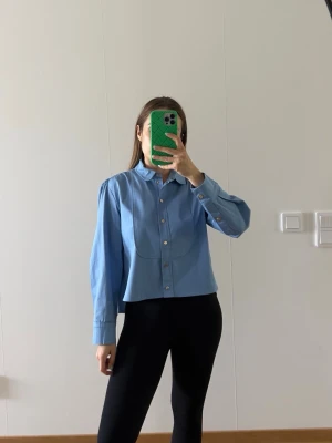 Maje shirt - Maje cropped button-up shirt in light blue. Structured silhouette with subtle gold button detailing. Elegant and easy to style for work or casual looks. Size XS / EU 34. New without tags. Retail price approx. £239.