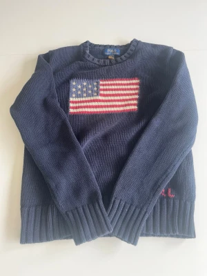 Mörkblå stickad tröja Polo Ralph Lauren - Hejsan, jag säljer min äkta stickade tröja från Ralph Lauren. Tröjan har en USA logga som motiv och är väldigt skön. Storlek är 164 men skulle säga att den passar 160-162 som bäst. Nypris är över 2500kr. Diskuterar gärna priset.