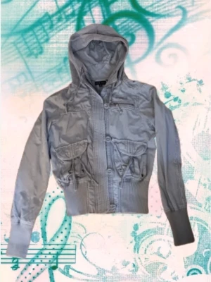 Blå croppad jacka från 00s - Ljus blå croppad jacka från bik bok med huva, stora fickor med snörning och ribbade muddar. Jackan har dragkedja och knappar framtill och är perfekt för dig som gillar en sportig och cool stil. Skickar mer bilder vid förfråga