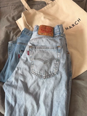 Levi's ljusblå raka jeans - Ljusblå raka jeans från Levi's med klassisk femficksdesign och hög midja. Jeansen har Levi's ikoniska läderpatch bak och röd logotagg på bakfickan. Tillverkade i slitstark denim, perfekta för en avslappnad och trendig look.