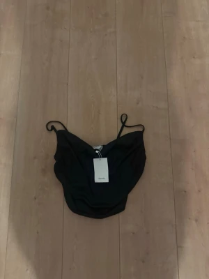 Svart baddräkt från Bershka - Snygg svart baddräkt från Bershka med tunna axelband och enkel, stilren design. Perfekt för dig som gillar minimalistisk stil på stranden eller vid poolen. Tillverkad i ett stretchigt material som sitter bekvämt.