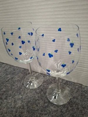 Vinglas, 2-pack - Två vinglas i klart glas med handmålade små blå frukter över hela kupan. Glasen har klassisk form med rund kupa och smal fot. Perfekta för att göra dukningen lite roligare och mer personlig.