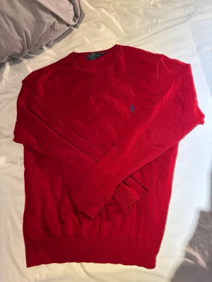 Röd tröja från Polo Ralph Lauren - Röd långärmad tröja från Polo Ralph Lauren i slim fit-modell. Tröjan har rund halsringning och den klassiska blå logotypen broderad på bröstet. Perfekt för dig som gillar stilrena och tidlösa plagg.