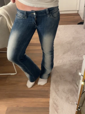 Blå bootcut jeans med slitningar - Säljer ett par blå cheap Monday bootcut jeans med snygga slitningar och ljusa partier framtill. Jeansen är i storlek 29/34, men de är uppsydda så de passar mig som är 165! 