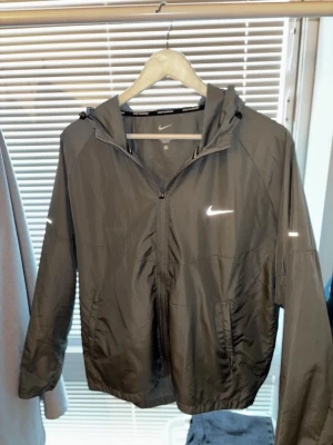 Nike Miller zipper  - Säljer en Nike Miller zipper i grå. Den är bara använd 2-3 gånger eftersom den är lite kort i armarna på mig. Längden är 67 cm och från hoodien ner till armarna är den 75,5 cm. Skriv om du undrar nåt. 