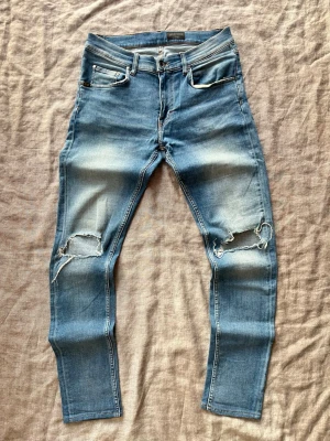 Blå tvättade slitna Tiger of Sweden jeans, 32/34 - Blå tvättade Tiger of Sweden jeans med hål vid knäna Inga defekter Hör av er vid frågor eller förhandling!