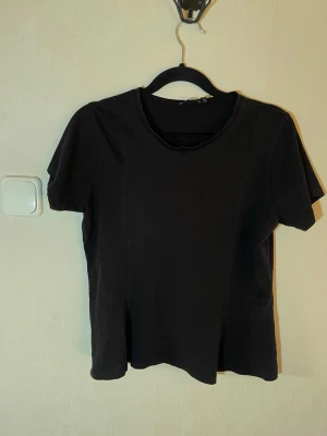 Svart basic t-shirt i bomull - En enkel svart t-shirt med rund hals och korta ärmar. Tillverkad i mjuk bomull som känns skön mot huden. Perfekt till jeans eller shorts för en clean och stilren look. Fint skick, inga skavanker. Boohoo, storlek 40. Djur, rök och parfymfritt hem. 