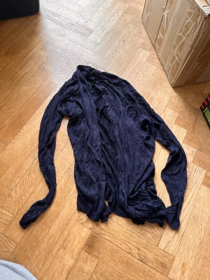 Mörkblå tunn kofta med prickar - Snygg mörkblå tunnstickad kofta med små vita prickar över hela plagget. Koftan har långa ärmar och ribbade muddar vid ärmslut och nederkant. Perfekt att slänga över en t-shirt för en chill look. Skriv gärna för mått! 💝