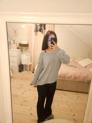 ljusblå kabelstickad tröja - Svingullig tröja som jag fått av min farmor för några år sedan, misstänker att den är köpt utomlands. Knappt använd så det är därför jag säljer den, inga defekter alls. Har en lös passform och en lite vidare v-neck så den kan sitta lite löst över axeln (som på bilden). Går att använda hela året om eftersom den ändå är hyfsat tunn men ändå långärmad och heltäckande. Har katt hemma men den skickas iväg nytvättad så det borde inte vara ett problem om du har allergi 🤍