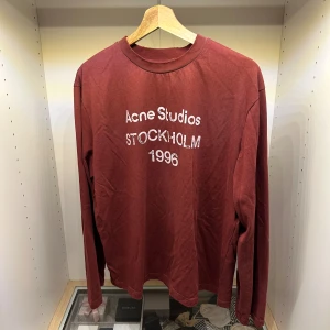 Röd Acne Studios Longsleeve ~ Unisex - Burgundy long sleeve T-shirt in a relaxed fit 🔷 🔷 Clean front print from Acne Studios featuring “Stockholm 1996” branding 🔷 Minimalist Scandinavian design with a subtle vintage feel 🔷 Deep burgundy color that adds a refined and versatile look 🔷 Soft cotton fabric for everyday comfort 🔷 Classic ribbed crewneck collar 🔷 Long sleeves for a relaxed and effortless style 🔷 Easy to style – works with both casual outfits and modern streetwear looks 🔷                                      🔷FitsM