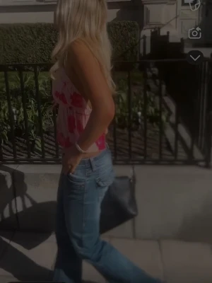 Rosa blommig linnetopp - Söt rosa linnetopp med blommigt mönster och tunna axelband. Toppen har en avslappnad passform och är perfekt för varma dagar. Materialet känns lätt och luftigt, vilket gör den skön att bära.